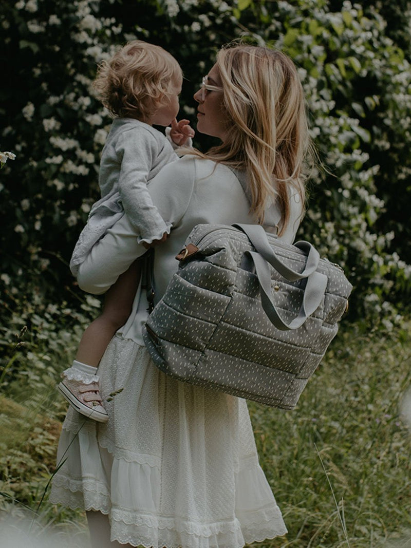 storksak organic cotton tote grey raindot, mum wearing as backpack and holding baby