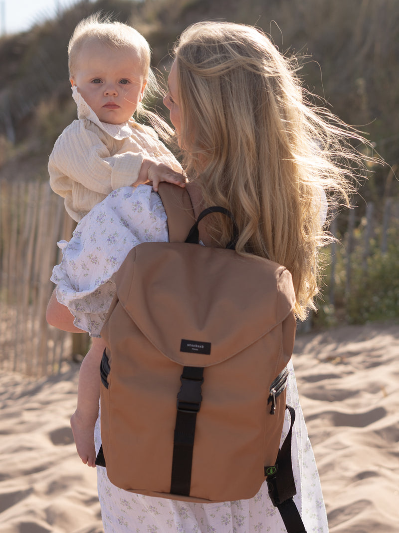 storksak trravel eco backpack diaper bag | mom carrying bag and holding baby