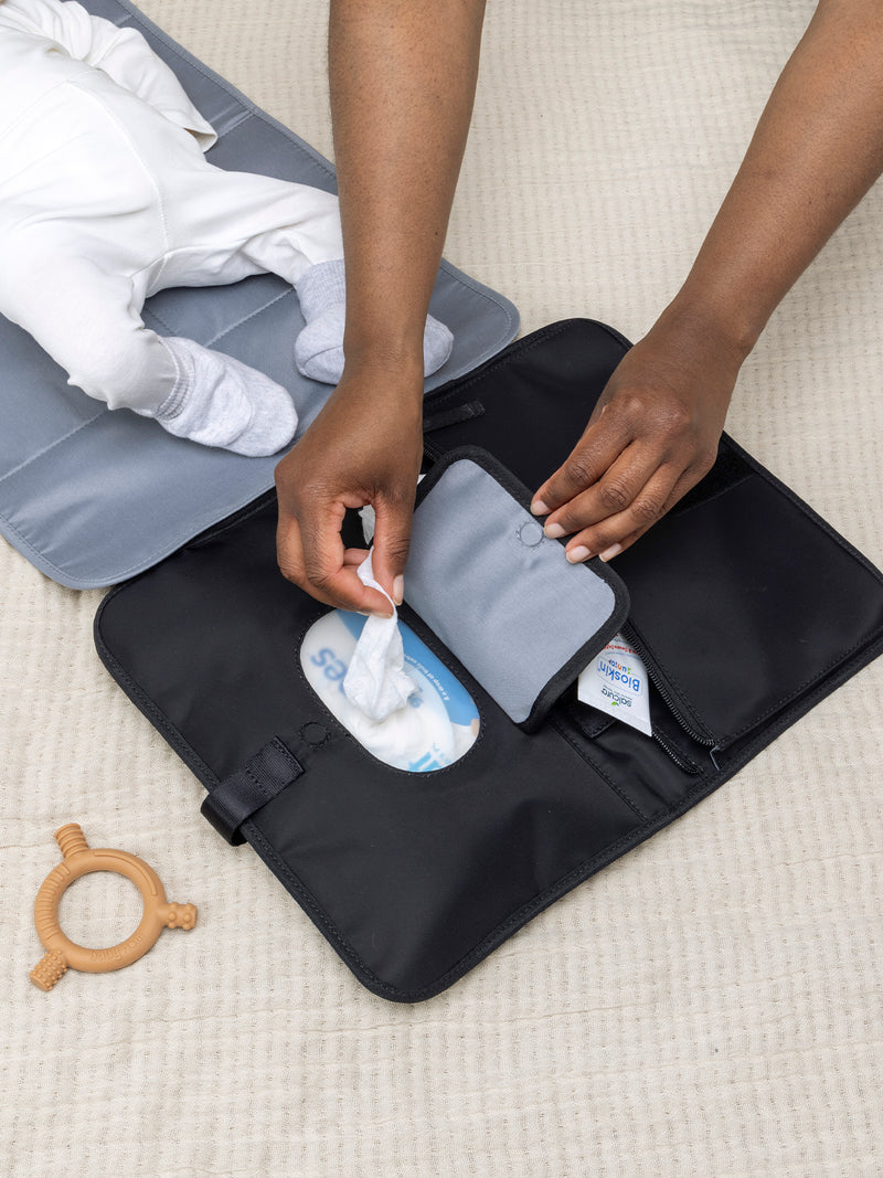 Storksak Change Station Black | baby laying on mat and mum getting wipes out of pocket