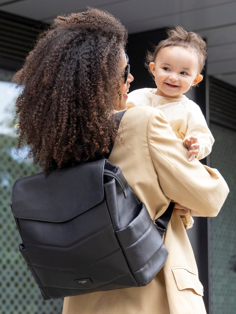  Storksak st james leather quilt black | mum wearing bag as backpack and holding baby