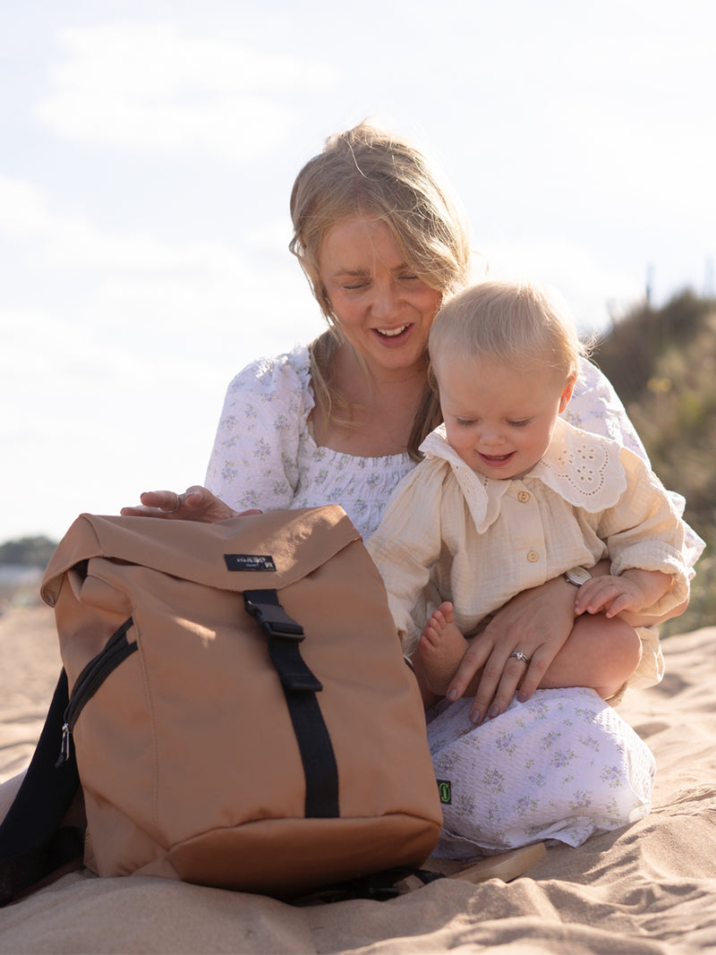 storksak trravel eco backpack diaper bag | mom at the beach with bag and baby