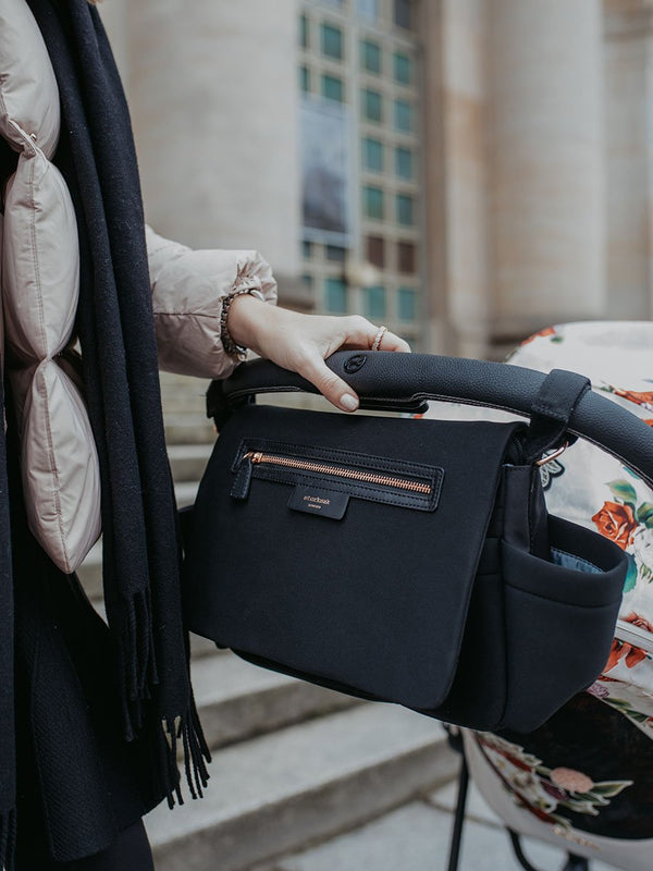 storksak stroller organiser luxe scuba black, attached to pram with mum holding stroller bar